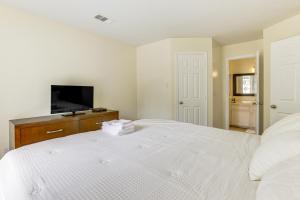 a white bedroom with a bed and a tv at Home 7 Mi to Energy Corridor Remote-Work Ready! in Houston