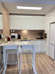 eine Küche mit weißen Schränken und einem Tisch und zwei Hockern in der Unterkunft Paris 42m Studio plus terrace in Paris