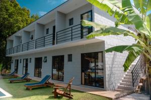 a white house with blue chairs in front of it at BoraMar Flats in Caraguatatuba