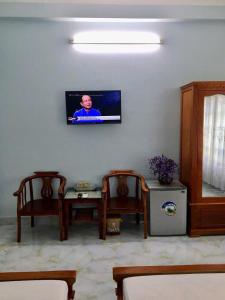 a living room with two chairs and a tv on the wall at Thảo Vân hotel in Sầm Sơn
