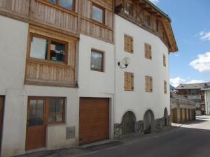 un edificio blanco con puertas de madera y garaje en Casa Podestà, en Moena