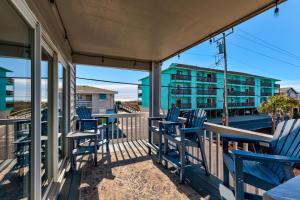 a deck with blue chairs and tables and a building at The Scallop by Carolina Beach Realty in Carolina Beach