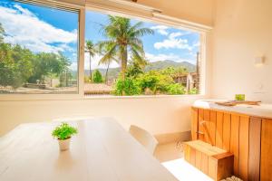 朱奎Casa d'Aroeira Residencial Boutique - Centro de Juqueí - 2 quadras do mar - Serviço de Praia - Roupa de Cama 600 fios algodão Egípcio - Toalhas Banho e Praia - Tudo Novo - Estacionamento Interno - Cozinha - Consulte unidades com Ofurô Hidro e Cromoterapia的带桌子和大窗户的餐厅
