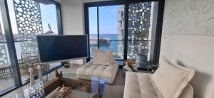 a living room with a tv and some chairs and windows at almoaj ,juman 2 marina view, in Ḩayl Āl ‘Umayr