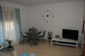 Una sala de estar con una mesa y un reloj en la pared. en Casa da Costa de Lavos, en Figueira da Foz
