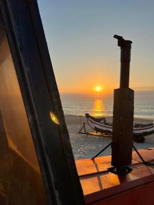 una puesta de sol en la playa con un barco en el agua en Casa da Costa de Lavos, en Figueira da Foz