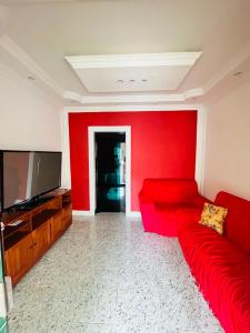 a living room with a red couch and a flat screen tv at Casa Completa - Cop 30 in Belém