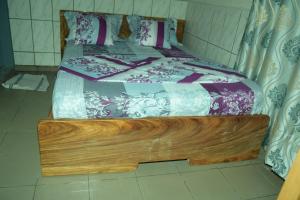 a bed in a room with a wooden frame at Grand Studio à 200 m de la plage de Kribi Clim - Wi-Fi in Kribi