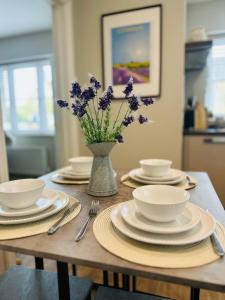 a table with plates and bowls and a vase of flowers at Lavender Lodge Bourton in Bourton on the Water +18 photos