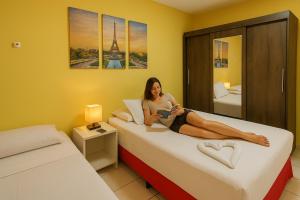 a woman sitting on a bed reading a book at Yacht Village Flat in Natal +43 photos
