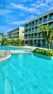 a large swimming pool in front of a building at Porto Alto Resort in Porto De Galinhas
