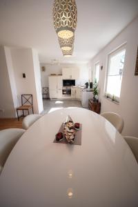 a white dining room with a table and a kitchen at Wohlfühloase - Moderne Ferienwohnung mit großem eingezäuntem Garten in Alleinlage an Feld & Wald, Natur pur trifft auf Komfort, Wellness und gute Erholung in Alpen