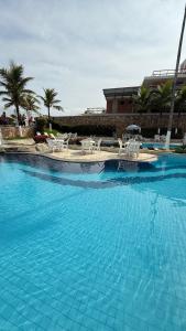 a large blue swimming pool with chairs and tables at Apart completo RESORT Pé na Areia RECREIO in Rio de Janeiro +2 photos