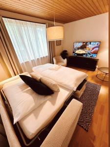a bedroom with a large bed and a flat screen tv at Gartenoase by Greatlifestay in Ennetbürgen