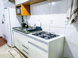 Una cocina blanca con estufa y fregadero. en Apto Aconchegante e Excelente localização, en Uberaba