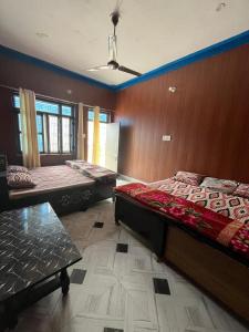 two beds in a room with wooden walls at Kartikey homestay and restaurant in Gopeshwar
