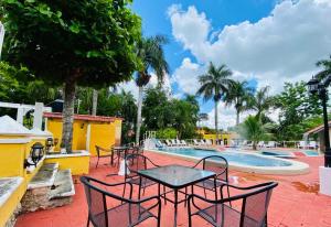 a patio with tables and chairs next to a swimming pool at Hotel Green River in Izamal
