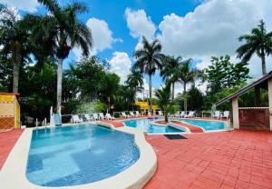 una piscina con palmeras y un cielo azul en Hotel Green River, en Izamal