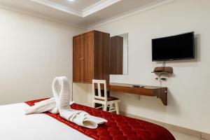 a bedroom with a bed with a desk and a tv at Hotel Lakshmi Grand in Chennai