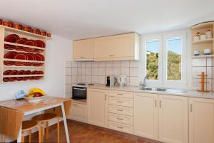 a kitchen with white cabinets and a wooden table at Mavroudis House Sifnos in Sifnos +13 photos