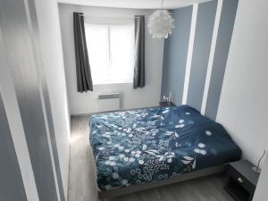 a bedroom with a bed with a blue comforter and a window at Grand appartement de ville avec 2 places de parking privées intérieur in Beuvrages