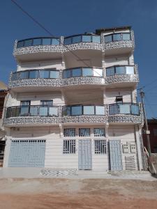 a tall white building with doors and windows at Deluxe in Ziguinchor