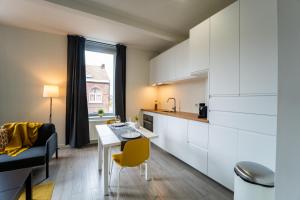 a kitchen with white cabinets and a table and chairs at Yellow Two in Mons +19 photos