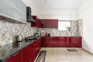 a kitchen with red cabinets and tiles on the wall at OBS Serviced Apartments HSR Layout Bangalore in Bengaluru