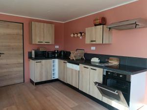 a kitchen with wooden cabinets and a black counter top at Le clos des papillons in Carly