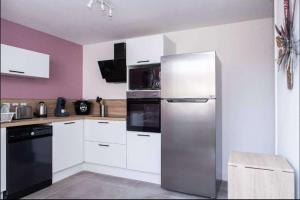 a kitchen with a stainless steel refrigerator and white cabinets at La Calaisienne - Grande maison 6 ch-Cinéma privé & bar-Tourcoing in Tourcoing