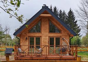 a log cabin with a porch and two chairs at Hygge z kominkiem i sauna Piasek Cedynia Chojna in Piasek