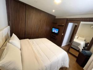 a bedroom with a white bed and a television at Casa Aconchego Canto da Viola in São Roque