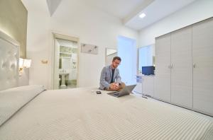 a man sitting on a bed with a laptop at Hotel Bristol in Bellaria-Igea Marina