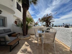 a patio with a table and chairs and a palm tree at Chalet en Mar Menor Urb las Góndolas in La Manga del Mar Menor