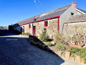 a stone building with a red door and a barn at Summerhill Byre in Ballymena