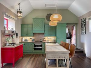 a kitchen with green cabinets and a red island at Summerhill Byre in Ballymena