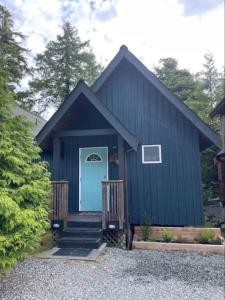 a blue house with a blue door and stairs at Tide and Trail- Cabin in Ucluelet in Ucluelet