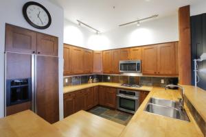 uma cozinha com armários de madeira e um relógio na parede em Big Beach Escape - Ucluelet - Sleeps 6 - Pet Friendly em Ucluelet