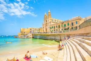 a group of people sitting on the beach near the ocean at Maltese Charm - Seaside Stay - Table Soccer in St. Julianʼs
