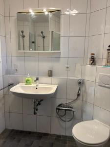 a bathroom with a sink and a toilet and a mirror at Duhner Leuchturm, Ferienwohnung DL02 in Cuxhaven +29 photos