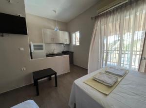 a room with a white table and a kitchen at Del Mar in Nea Vrasna