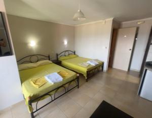 two beds in a room with yellow sheets at Del Mar in Nea Vrasna