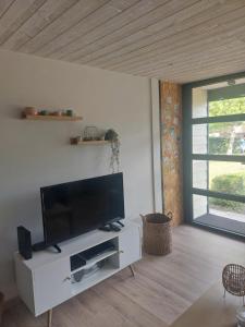 a living room with a flat screen tv on a white cabinet at chalet la rose des sables in Labenne