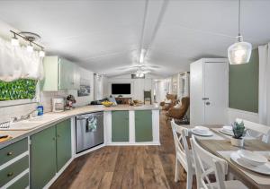 eine Küche mit grünen Schränken und einem Esstisch in der Unterkunft Hot Tub, Fire pit & Pet-friendly Riverside Retreat in New Braunfels + 37 Fotos