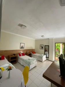 a hotel room with two beds and a table and chairs at Hotel Charme Fonte do Boi in Salvador