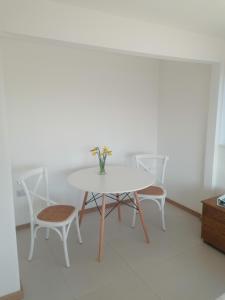 a white table and chairs with a vase of flowers on it at The Croft in Whale Islet +26 photos