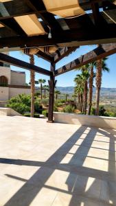 a patio with awning and palm trees in the background at قصر تل الرمان in Ar Rummān