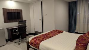 a bedroom with a bed and a desk and a chair at Grand Plaza Hotel in Kampala
