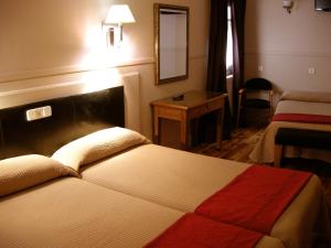 a hotel room with a bed and a table at Hostal Canovas in Cuenca