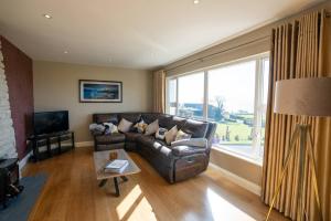 a living room with a leather couch and a large window at Inch by the Sea - Sea Views in Inch